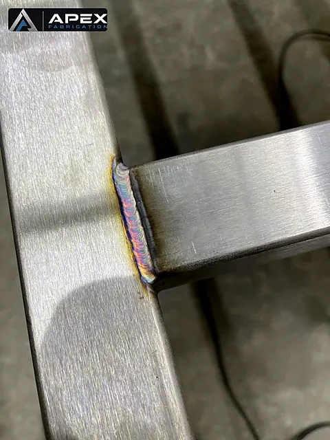 TIG-welded joint between brushed stainless steel tube and flat bar with colorful heat tint