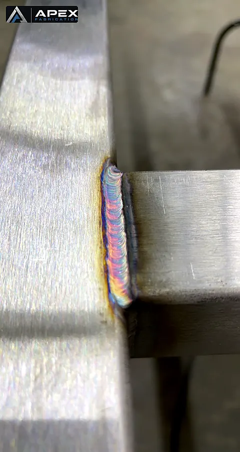 Detailed stacked-dime TIG weld bead connecting stainless steel tubing to a flat stainless member