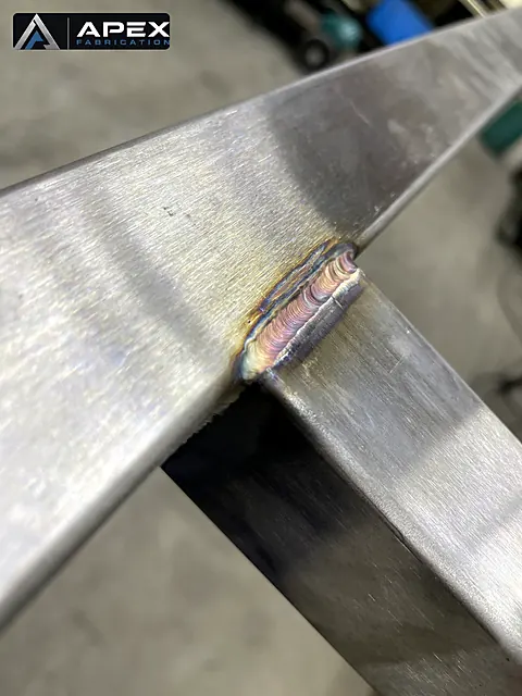 TIG weld with heat coloration at an angled joint between two stainless steel tube sections