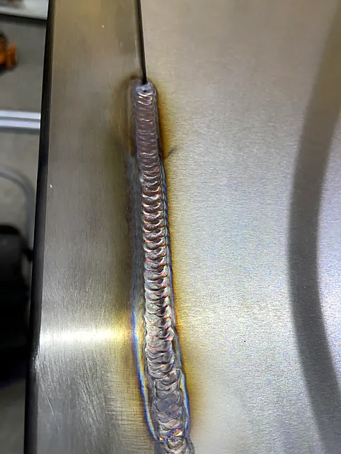 Long stacked-dime TIG weld seam running between two brushed stainless steel panels