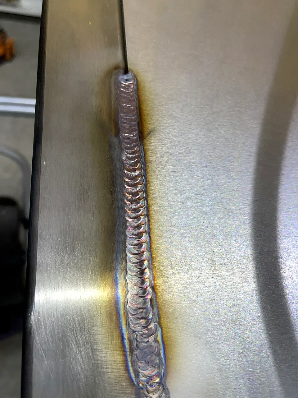 Long stacked-dime TIG weld seam running between two brushed stainless steel panels