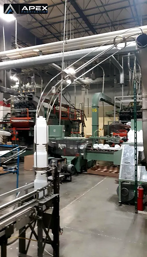 Overhead air conveyor lines routing plastic bottles across a molding and filling plant