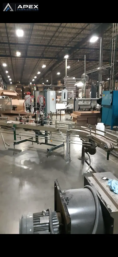 Table-top chain conveyors and filling equipment spanning a bottling warehouse floor