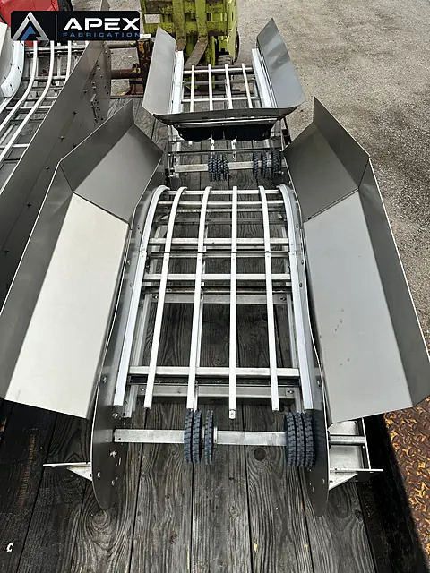 Stainless steel conveyor curve sections with sprockets and flared side guards staged for shipment