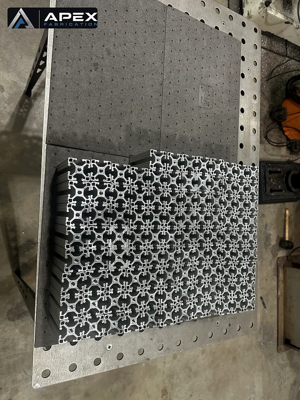 Stack of precision CNC-cut aluminum plates with repeating pattern on a fabrication table