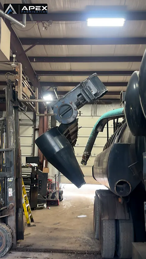 Large steel cyclone separator cone held in position beside a tanker unit inside the shop