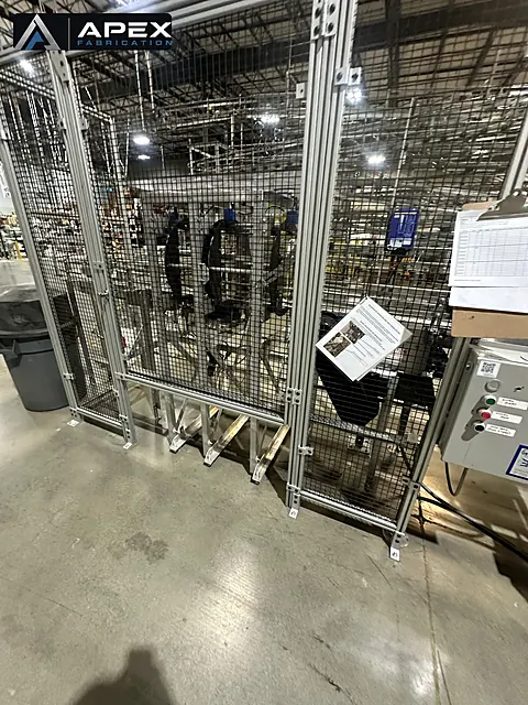Wire mesh safety guarding with aluminum extrusion framing installed around automated equipment on a plant floor