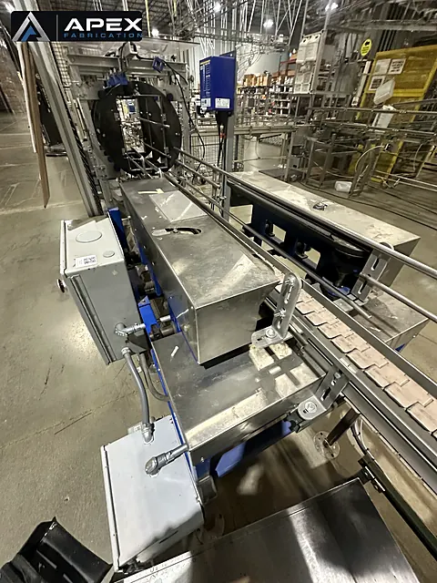 Wrapper machine with stainless steel covers and chain conveyor feeding through a packaging line