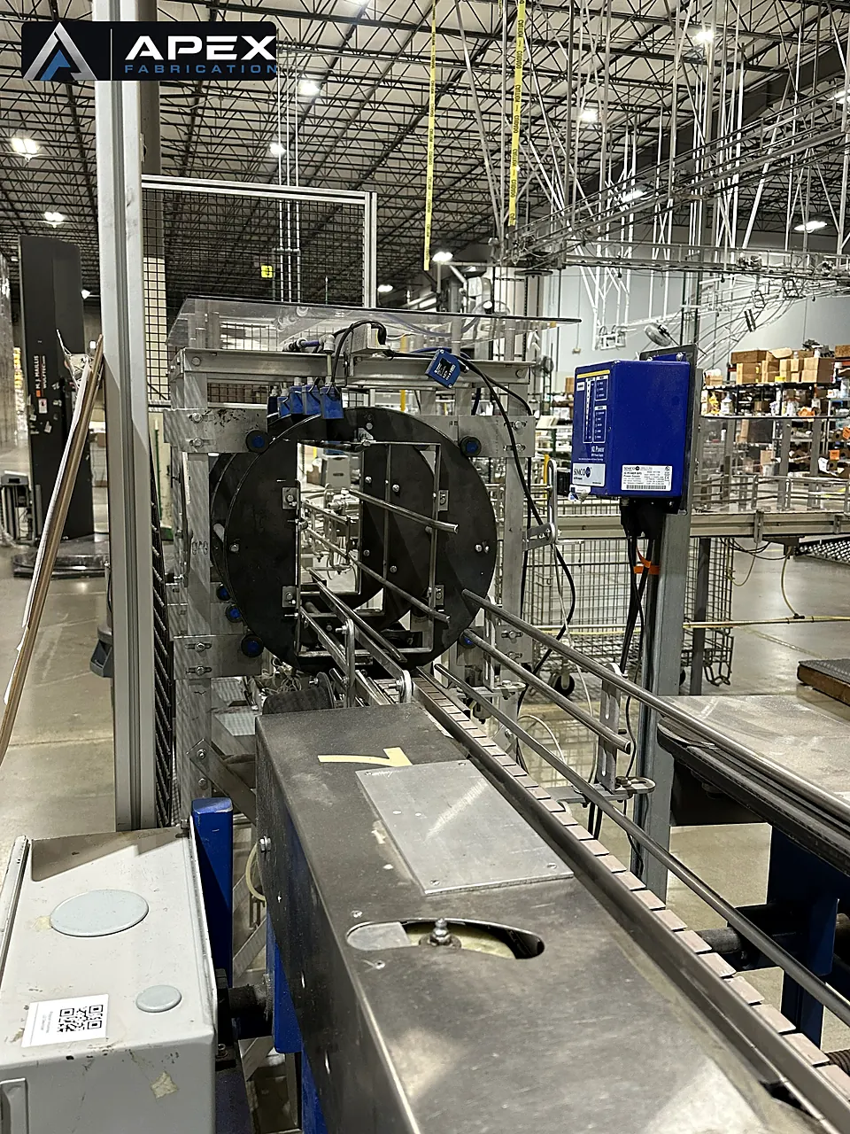 Orbital wrapping machine with large rotating ring and stainless infeed conveyor on a production line