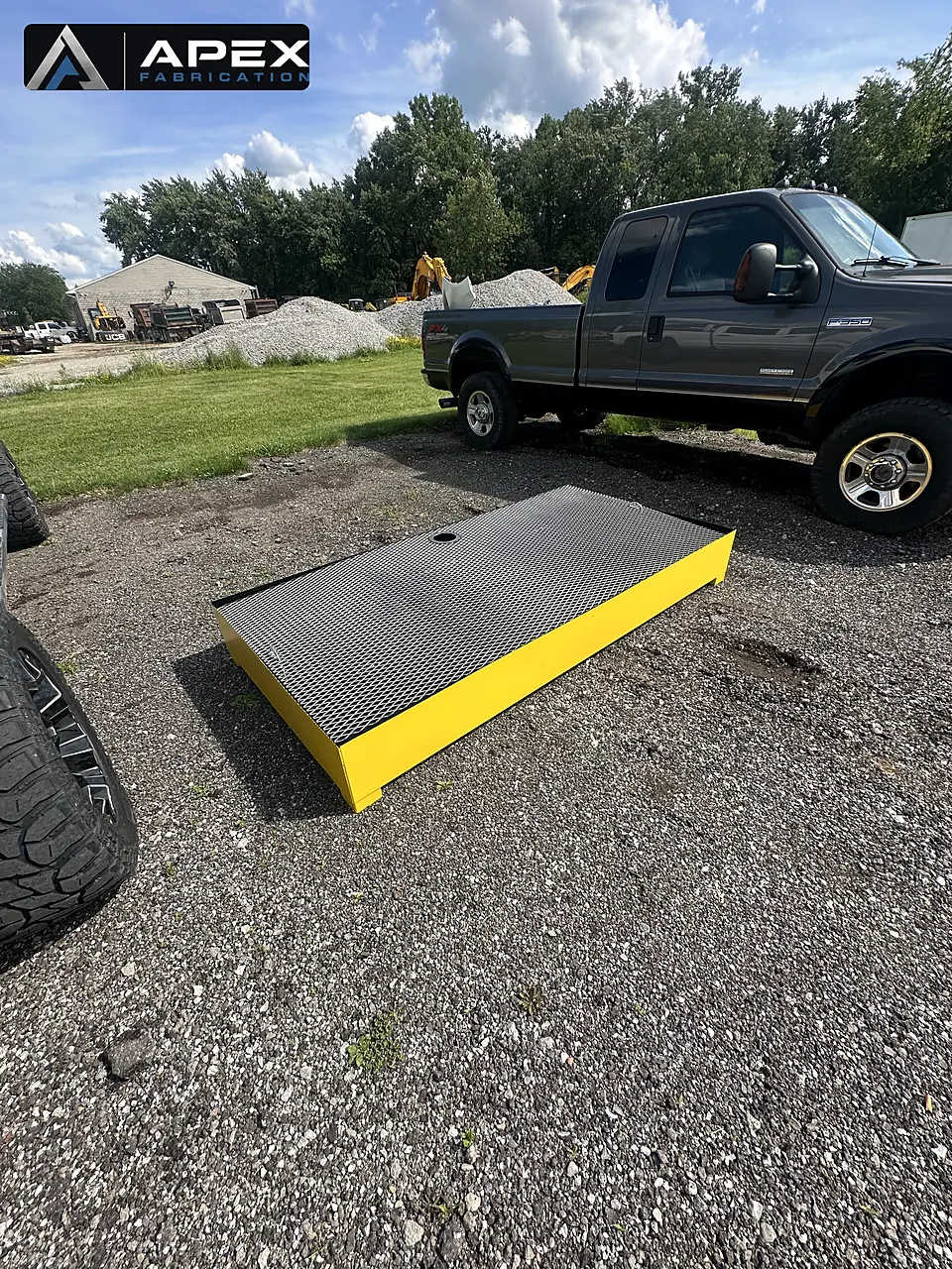 Completed yellow spill containment platform with grating deck staged in the gravel yard