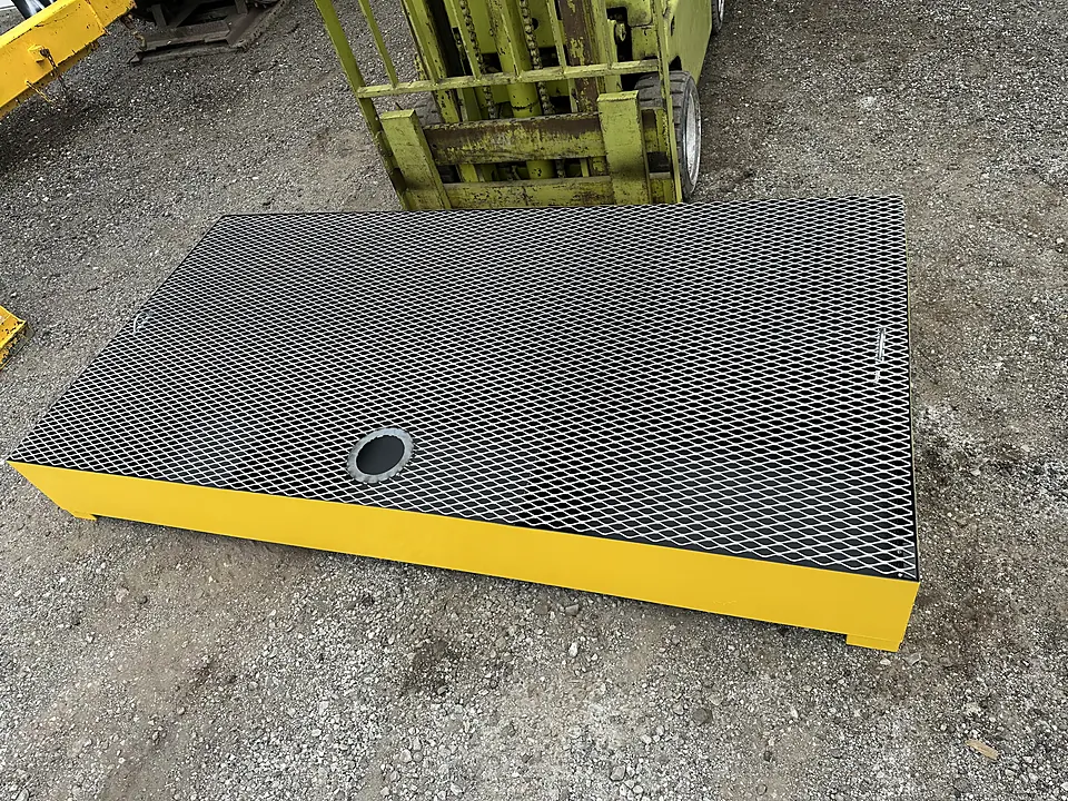 Yellow spill containment platform with black expanded-metal grating deck and drain fitting