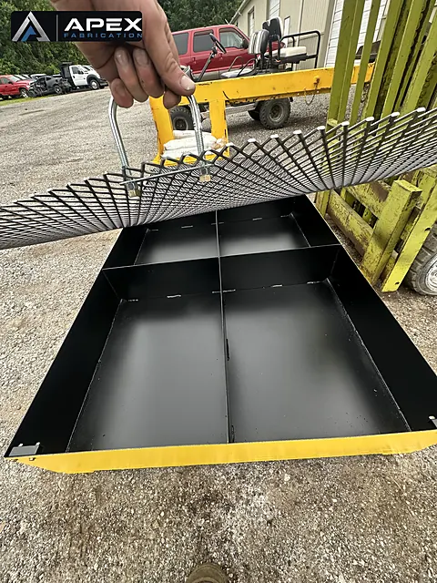 Removable grating panel lifted to show black-coated compartments inside a containment platform