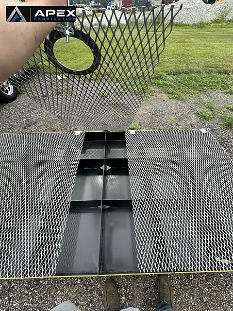 Expanded-metal grating panels over black steel compartments of a containment platform
