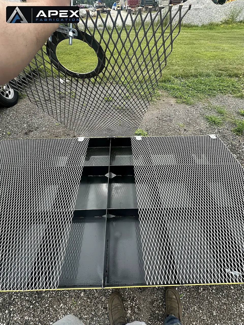 Expanded-metal grating panels over black steel compartments of a containment platform