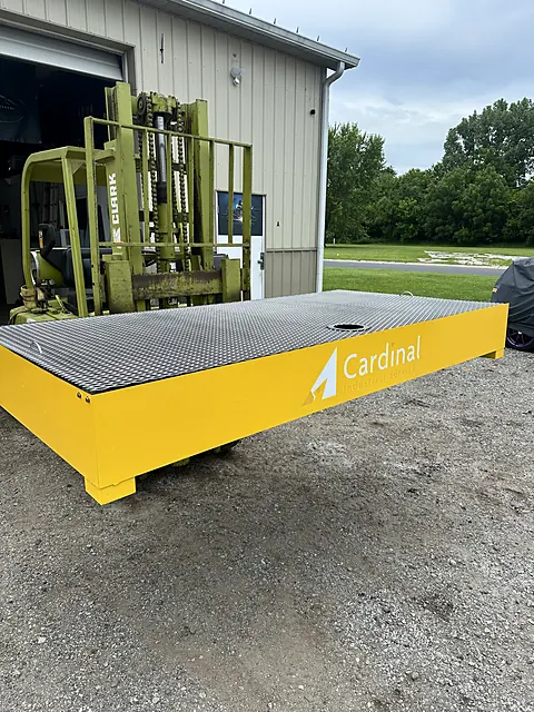 Yellow powder-coated IBC spill containment platform with grating deck, branded for the customer