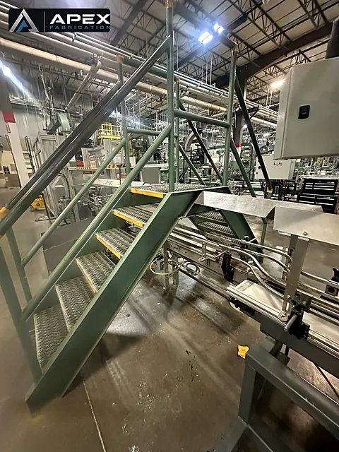 Fabricated steel crossover stairs with tread plating installed above a plant conveyor