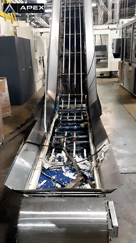 Fire-damaged stainless incline conveyor in a production plant awaiting repair