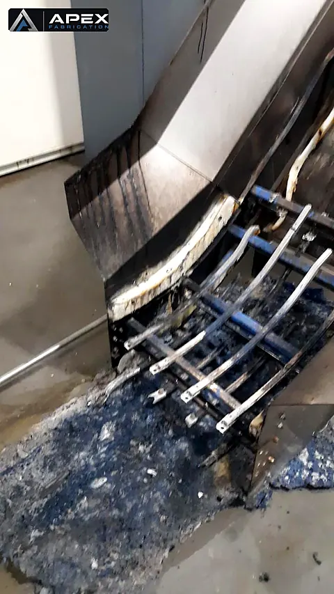 Fire-damaged conveyor chute and guide rails with melted debris, documented before repair