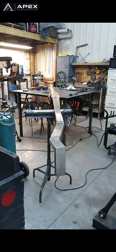 Zig-zag formed stainless steel component fixtured upright on a stand in the fabrication shop
