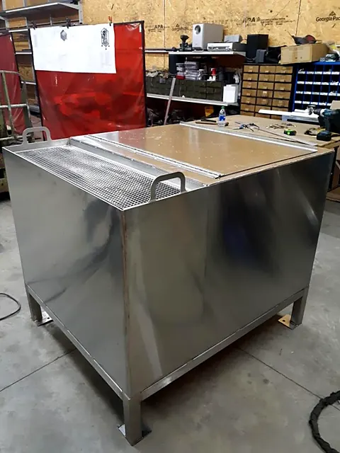 Polished stainless steel tank with grated lid and welded legs completed in the fabrication shop