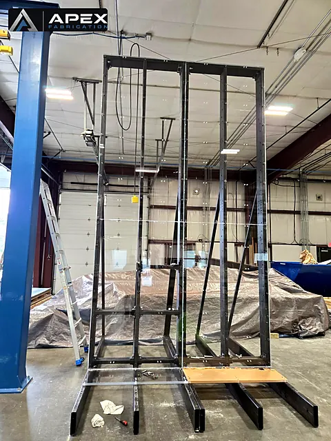 Tall welded steel A-frame rack structure standing on the floor of a fabrication shop