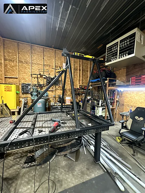 Steel A-frame stand under fabrication on a welding table with a level checking the top rail
