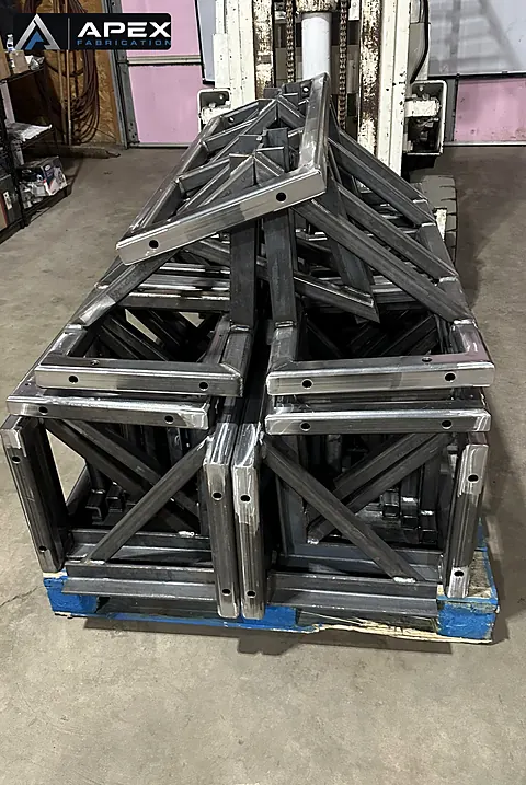 Pallet of batch-welded steel truss frames stacked on a forklift after fabrication