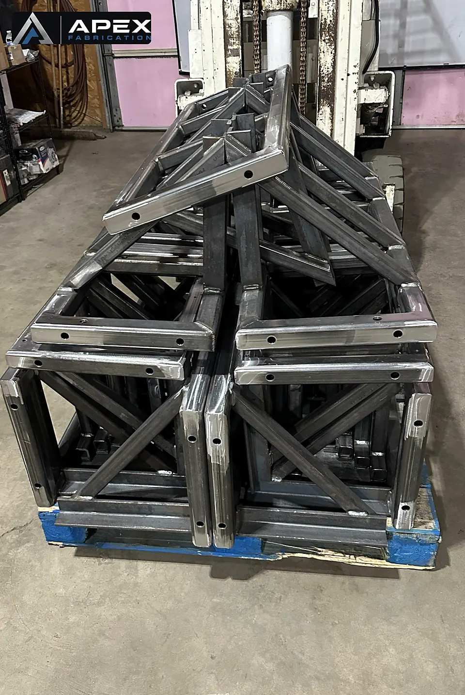 Pallet of batch-welded steel truss frames stacked on a forklift after fabrication
